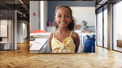 Portrait of smiling african american elementary schoolgirl standing in classroom Wall mural