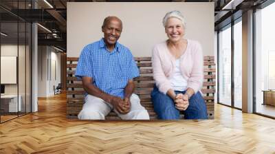 Portrait of smiling senior woman and man sitting on bench Wall mural