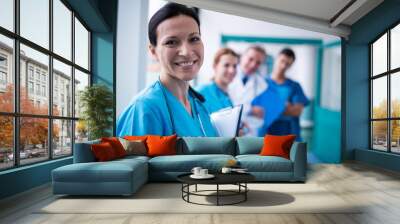 portrait of smiling surgeon holding a clipboard in corridor Wall mural