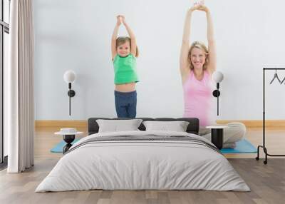 Pregnant mother and daughter doing yoga together Wall mural