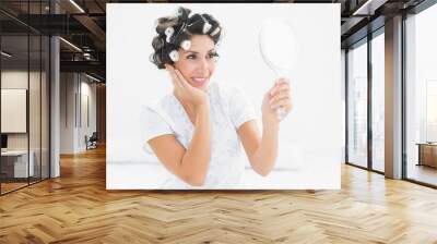 Pretty brunette in hair rollers looking in hand mirror Wall mural