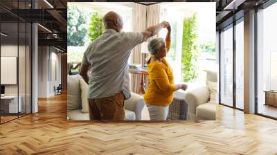 Senior african american couple dancing together in living room smiling Wall mural