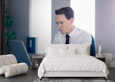 Serious businessman typing on laptop Wall mural