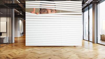 Shocked male eyes spying through roller blind Wall mural