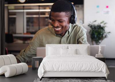 Smiling african american young businessman using laptop in creative office Wall mural