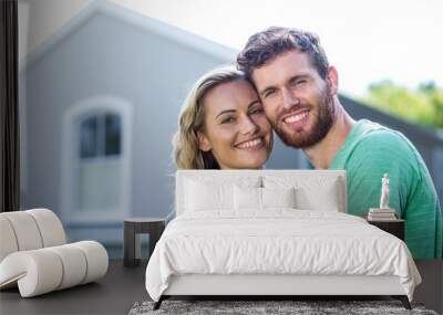 Smiling couple standing against house Wall mural