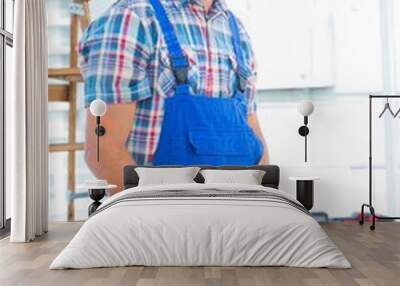 Smiling handyman using tape measure at workbench in office Wall mural