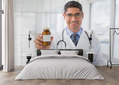 Smiling male doctor with a bottle of pills in hospital Wall mural