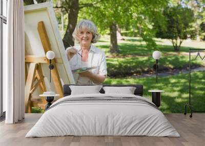 smiling mature woman painting in park Wall mural