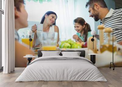 Smiling parents talking with their daughter at breakfast table Wall mural