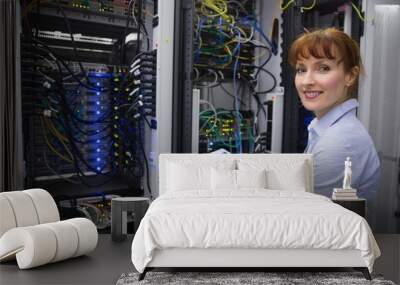 Smiling technician using tablet pc while analysing server Wall mural