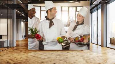 Smiling three chefs holding a vegetables Wall mural