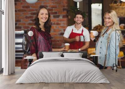 Smiling waiter and two customers looking at the camera Wall mural