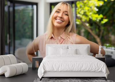 Smiling woman in casual attire standing confidently in bright living room Wall mural