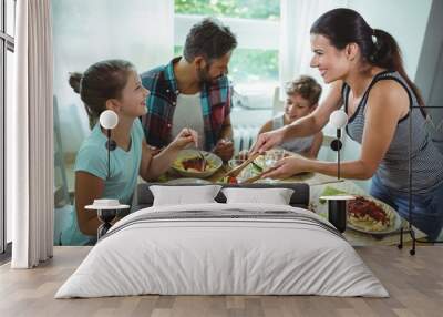 Smiling woman serving meal to her family Wall mural