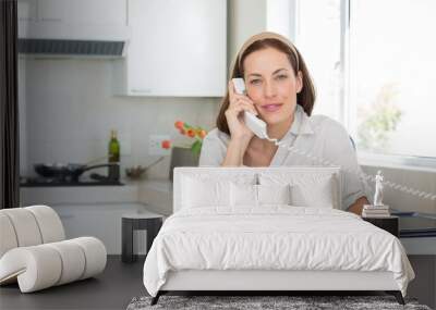 smiling woman with coffee cup using landline phone in kitchen Wall mural