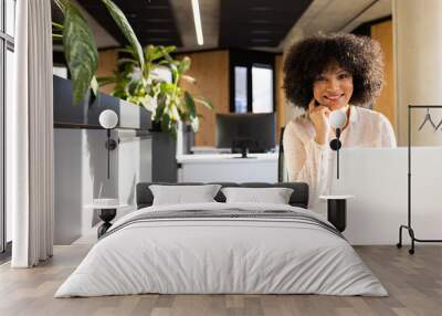 Smiling woman working on laptop with smartphone on desk in modern office, copy space Wall mural