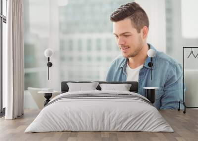 Smiling young man working on laptop  Wall mural