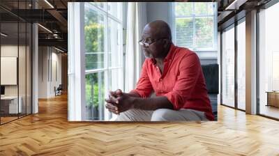 Thoughtful mature african american man looking though window while sitting at home, copy space Wall mural