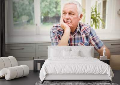 Thoughtful senior man sitting at table Wall mural