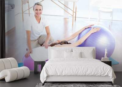 Trainer helping woman with exercise ball Wall mural