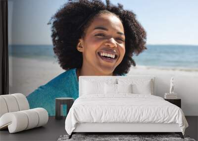 Unaltered portrait of happy african american woman looking at camera and smiling on beach Wall mural