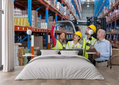 Warehouse manager and co-workers discussing over clipboard Wall mural