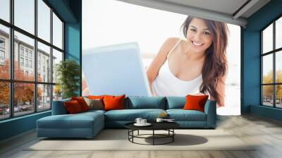 woman lying across the bed, with her laptop beside her, and smil Wall mural