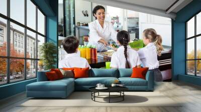 Woman serving food to children Wall mural