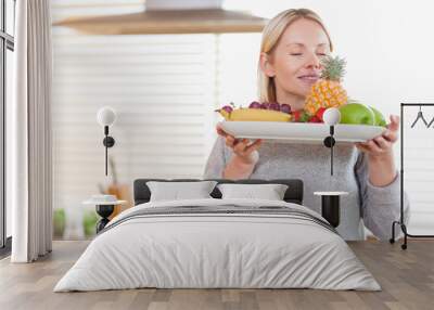 Woman smelling on her fruit plate Wall mural