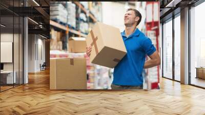 Worker with backache while lifting box in warehouse Wall mural