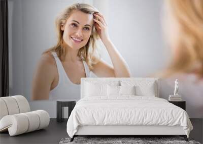 young woman checking her hair in bathroom mirror Wall mural