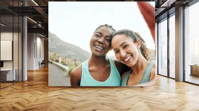 Documenting our fitness journey. Shot of two young women taking a selfie while exercising in nature. Wall mural