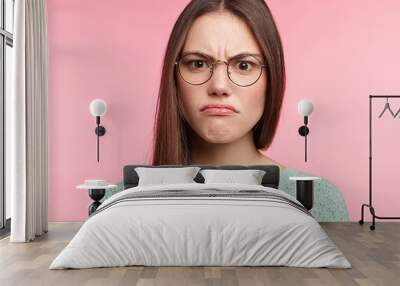 Aggravated brunette female with long straight dark hair, wears spectacles, frowns face in discontent, feels displeasure, being insult by someone. Headshot of Asian woman has annoyed expression Wall mural