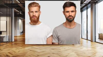 bearded serious male friends with trendy haircut, stand close to each other, think where spend free  Wall mural