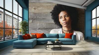 Beauty and skin care concept. Headshot of fashionable dark-skinned young woman with stylish haircut and clean healthy skin looking away with serious and pensive expression, resting against wooden wall Wall mural