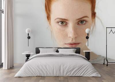 Close up highly-detailed picture of beautiful charming young female with perfect freckled skin, ginger hair and green eyes resting indoors, dressed in sailor t-shirt. Teenage girl posing in studio Wall mural