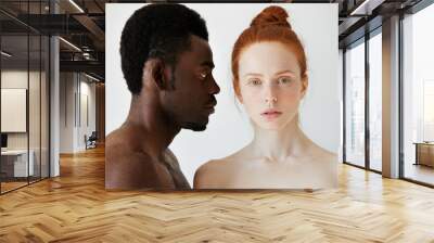 Coffee and milk. Portrait of young mixed race couple posing naked against white studio wall. Profile of African man looking at his Caucasian girlfriend with love and affection. Interracial relations Wall mural