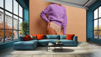 Cropped image of faceless woman with slender legs slim figure wears purple knitted jumper and panties has healthy dark skin poses indoor Wall mural