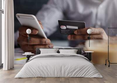 Cropped shot of African-American businessman paying with credit card online making orders via Internet. Successful black male holding plastic card making transaction using mobile banking application Wall mural