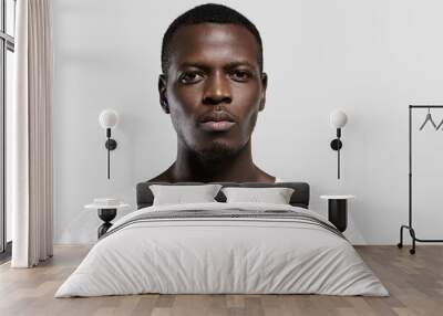 Headshot of attractive serious African student with small beard and moustache, dressed in casual t-shirt, looking at camera with confident and thougthful expression on his face standing at gray wall Wall mural