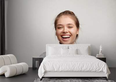 Headshot of good-looking lucky woman with tied hair pure skin and broad smile being happy to watch at camera. Sincere female with beautiful appearance wearing casual clothes isolated over white wall Wall mural