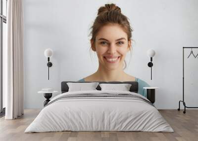 Headshot of pleasant-looking young Caucasian woman with broad smile showing her straight white teeth being happy with positive news. Woman with pleasant smile posing against white background Wall mural