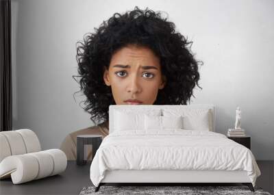 Headshot of regretful young mixed race woman feeling sorry for doing something wrong, looking at camera with brows frowned, doing her best to get forgiveness from her boyfriend during quarrel Wall mural