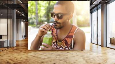 healthy organic food. half profile portrait of dark skinned guy drinking tasty fresh green smoothie  Wall mural