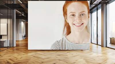 Heterochromia concept. Attractive young woman with ginger hair and different colored eyes smiling happily, posing isolated against white studio wall with copy space for your informational content Wall mural