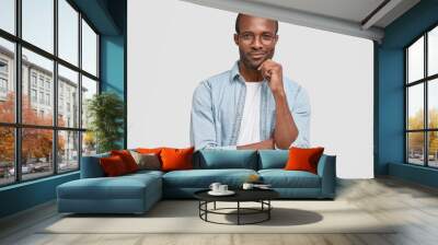 Horizontal shot of confident dark skinned male looks seriously at camera, has intention to do something, keeps hand under chin, wants to express his innovative idea for colleagues at meeting Wall mural