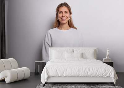 Horizontal shot of delighted young European woman dressed in casual clothes smiles gladfully being happy to get new job isolated over white background. People lifestyle and emotions concept. Wall mural