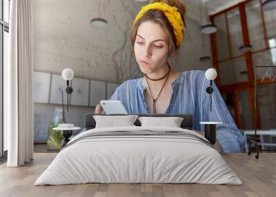 Human and technology. People and education conept. Beautiful European woman in casual clothes studying biology at classroom having some doubts checking information in telephone using internet Wall mural