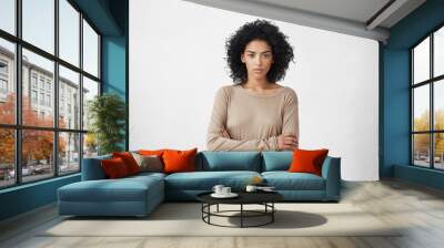 Indoor shot of angry grumpy young mixed race female dressed casually keeping arms folded, looking at camera with strict and skeptical expression, doesn't believe excuses of her unfaithful boyfriend Wall mural